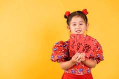 快乐亚洲中国人女孩微笑穿红色的旗袍旗袍持有报业红色的包货币礼物