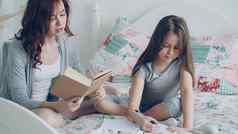 年轻的妈妈。帮助可爱的女儿家庭作业小学学校爱的妈妈阅读书女孩写作笔记字帖坐着床上首页