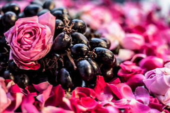 关闭拍摄生新鲜的群葡萄红色的粉红色的玫瑰花黑色的木董事会