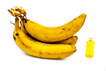 关闭拍摄香蕉石油玻璃瓶异戊基醋酸新鲜的黄色的香蕉孤立的白色