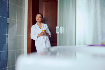 华丽的自信可爱的女人白色浴袍站舒适的首页浴室玻璃柠檬水手
