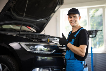 肖像车机械师车车间显示拇指背景服务积极的汽车服务工人微笑相机显示拇指手势批准车修复车间