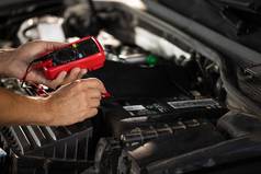 机械师车检查测试车电池测试人员检查电池电压电万用表男人。万用表测量电压电池