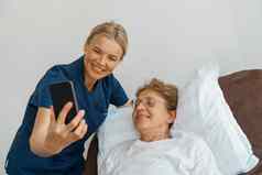 医生护士有爱心的上了年纪的女人移动电话需要自拍医院房间