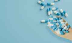 前视图蓝白色抗生素胶囊药片木勺子蓝色的背景抗生素药物电阻处方药物医疗护理制药护理抗菌药物过度使用