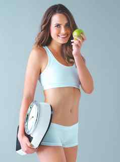 健康的身体健康的心健康的精神工作室拍摄健康的年轻的女人持有规模苹果灰色背景