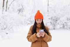 美丽的亚洲女人走公园电话在线购物冬天雪一天