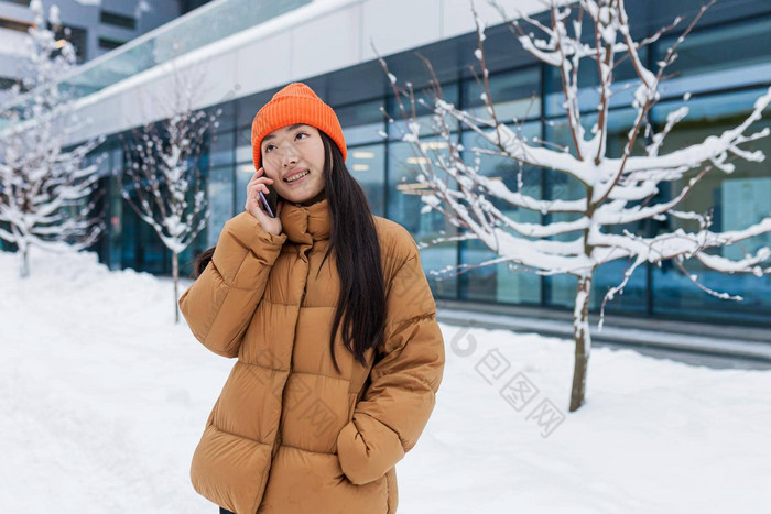 兴奋快乐朝鲜文女人会说话的移动电话笑听到好新闻肖像快乐的亚洲赶时髦的人持有智能手机