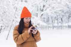 美丽的亚洲女人走公园电话在线购物冬天雪一天