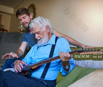 教学即兴小段快乐年轻的男人。教学上了年纪的祖父玩电吉他沙发上首页