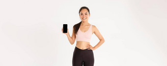 体育运动技术活跃的生活方式概念适合苗条的可爱的亚洲健身女孩女运动员运动服装推荐锻炼应用程序显示智能手机屏幕微笑