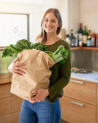 新鲜的杂货商肖像微笑年轻的女人站厨房携带纸袋完整的食品杂货