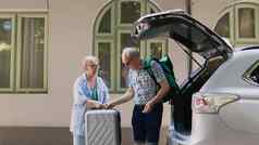 退休夫妇加载旅行行李车树干