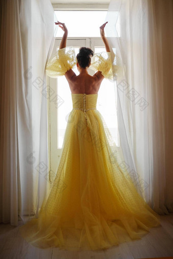 女人的轮廓金豪华的<strong>衣服</strong>背景窗口持有窗帘手优雅的夫人黄色的长<strong>丝绸衣服</strong>只回来回来视图