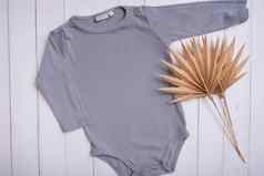 灰色婴儿紧身衣裤模型标志文本设计木背景棕榈叶子前视图