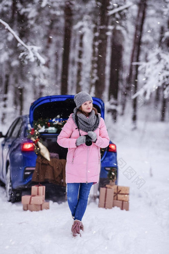 女人冬天白雪覆盖的森林树干车装饰圣诞节装饰