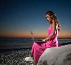 美丽的女孩移动PC粉红色的衣服海岩石