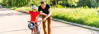 快乐家庭父亲教孩子女儿骑自行车公园自然