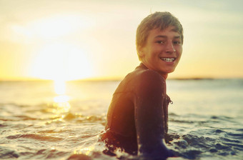 冲浪者微笑肖像年轻的男孩潜水服坐着冲浪板海洋