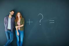 数学年轻的夫妇站前面黑板上符号写