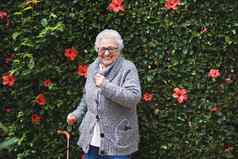 有趣的女人跳舞听音乐智能手机穿耳机微笑享受有趣的庆祝退休花园花墙