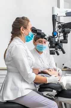 女牙医牙科显微镜治疗病人牙齿牙科诊所办公室