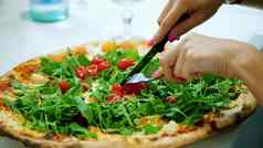 特写镜头大多汁的热披萨绿色芝麻菜樱桃西红柿女手减少披萨刀叉