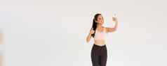 完整的长度微笑女生活方式博主亚洲健身女孩运动服装采取自拍健身房显示竖起大拇指演示锻炼exercies追随者在线生活流培训