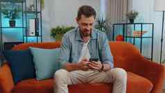 肖像成人男人。坐着沙发智能手机分享消息社会媒体应用程序