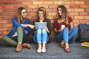 令人心寒的校园微笑女大学学生坐着校园数字平板电脑
