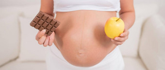 怀孕了女人持有苹果酒吧巧克力第九月怀孕