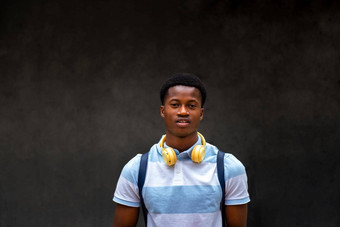 肖像青少年非洲美国学生男孩相机在户外黑暗混凝土墙背景复制空间