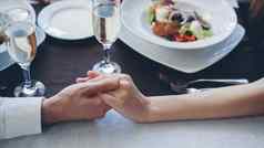 特写镜头拍摄年轻的情人触碰持有手优雅的餐厅表格闪闪发光的香槟眼镜餐具食物背景