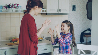 快乐妈妈。可爱的有趣的女儿玩鼓掌手游戏有趣的烹饪厨房首页家庭烹饪人概念