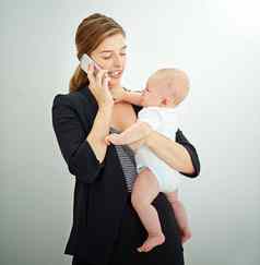 采取护理婴儿业务成功的年轻的女商人携带可爱的婴儿男孩会说话的电话
