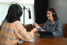 友好的女广播公司穿耳机面试客人小广播工作室