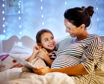 谁挑选故事今晚有吸引力的年轻的怀孕了女人阅读女儿睡觉前故事平板电脑