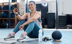 女人采取自拍电话锻炼健身房阅读社会媒体帖子放松有氧运动健身锻炼俱乐部运动员女孩移动应用程序体育培训地板上