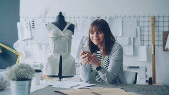 有创意的服装设计师智能手机画草图工作现代裁缝商店缝纫表格女人忙涉及到过程