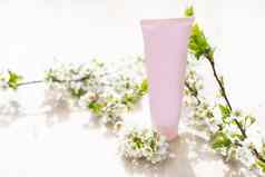白色空白化妆品管瓶花盛开的分支粉红色的背景自然有机水疗中心化妆品美概念模型前面视图