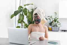 中期成人女人粘土面部面具穿浴毛巾移动PC