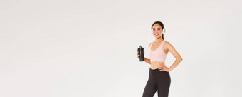完整的长度苗条的健康的亚洲女孩健身女阿塞尔特锻炼健身房听<strong>音乐</strong>无线耳机喝水瓶活跃的<strong>培训</strong>白色背景