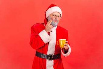 肖像上了年纪的男人。灰色的胡子穿圣诞老人老人服装痛苦可怕的<strong>牙齿疼痛</strong>喝热冷饮料
