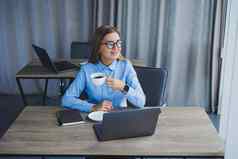 美丽的业务女人衬衫眼镜坐在移动PC办公室表格女人经理眼镜工作场所现代办公室工作一天电脑