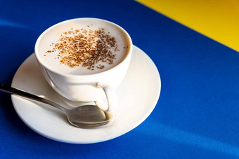 卡布奇诺咖啡蓝色的背景白色杯勺子咖啡豆子早....咖啡意大利传统的意大利早餐小白色陶瓷杯咖啡科普兹空间