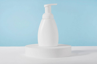 浴肥皂白色化妆品瓶模型白色讲台上基座蓝色的背景身体护理泡沫产品乳液包装塑料化妆品管前面视图模拟