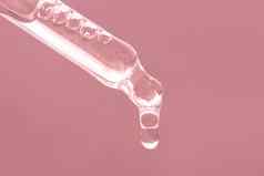 特写镜头粉红色的下降下降下降关闭美皮肤护理产品吸管至关重要的石油血清肽透明质酸酸粉红色的背景护理