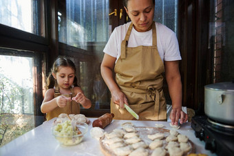 妈妈女儿成型饺子漂亮的女人家庭主妇烹饪乌克兰瓦雷尼基农村夏天厨房