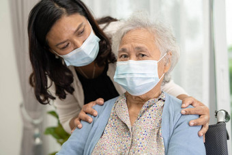 照顾者亚洲高级上了年纪的夫人女人坐着轮椅穿脸面具保护安全感染科维德冠状病毒