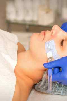 美容师覆盖女人面部皮肤保湿清洗面具皮肤护理过程水疗中心美沙龙